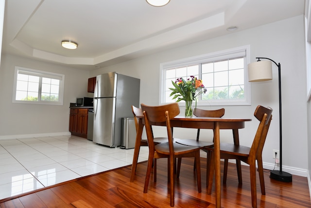 dining space with light hardwood / wood-style flooring and a tray ceiling