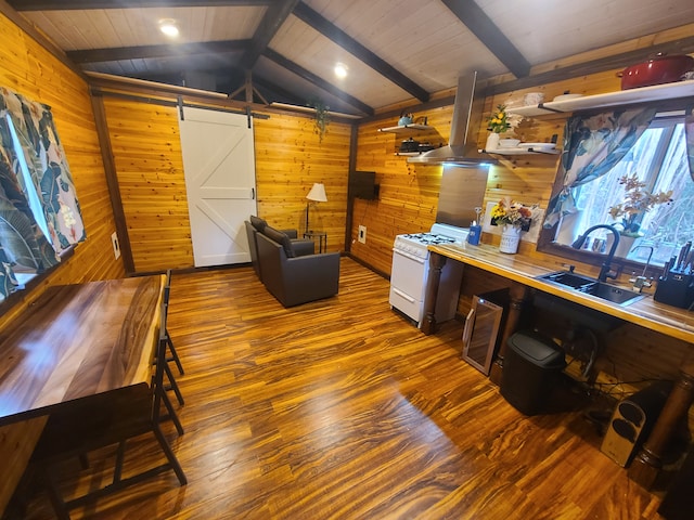 office area with wooden walls, a barn door, hardwood / wood-style flooring, lofted ceiling with beams, and sink