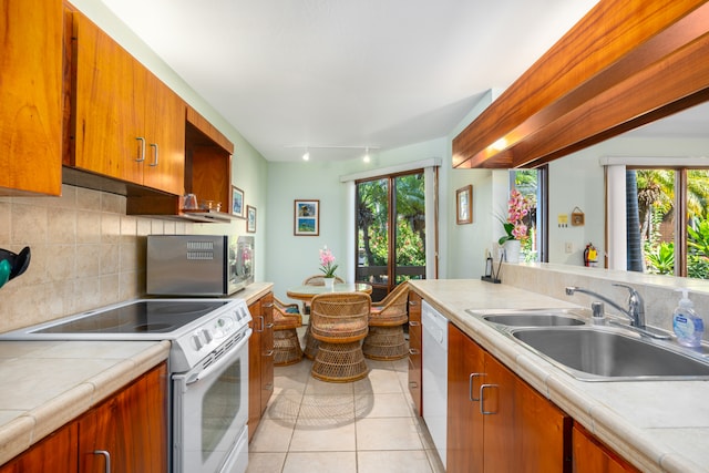 kitchen featuring white appliances, rail lighting, backsplash, sink, and light tile patterned flooring