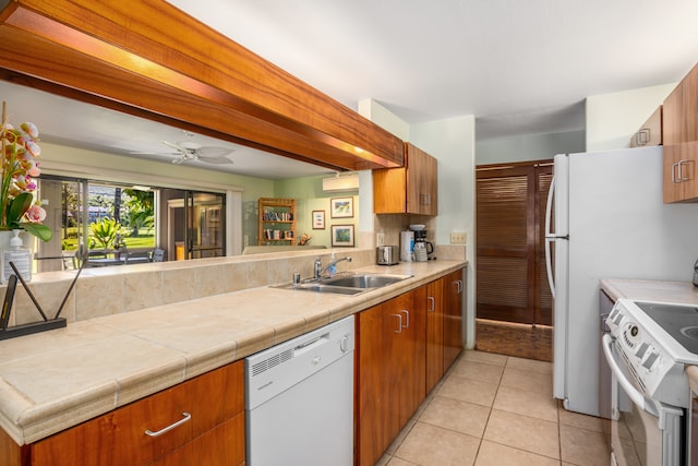 kitchen featuring white appliances, tile counters, sink, ceiling fan, and light tile patterned flooring