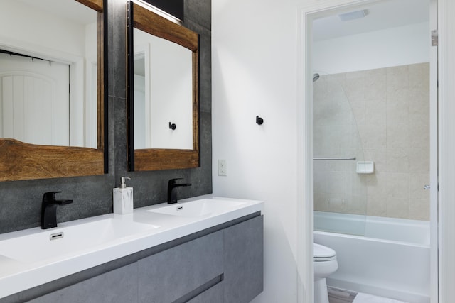 full bathroom with vanity, tiled shower / bath combo, and toilet