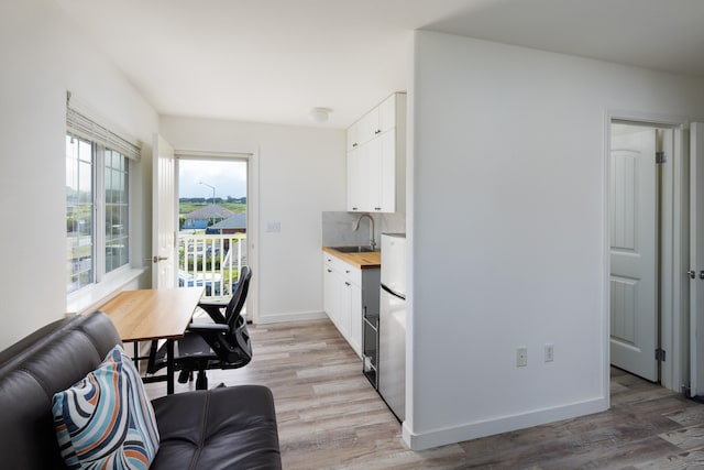 kitchen featuring wood counters, white cabinetry, sink, decorative backsplash, and light hardwood / wood-style flooring