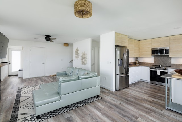 kitchen with ceiling fan, backsplash, hardwood / wood-style floors, stainless steel appliances, and light brown cabinetry