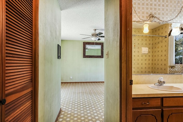 bathroom with ceiling fan, vanity, and a textured ceiling