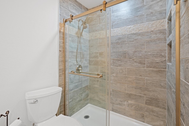 bathroom featuring toilet and a shower with door