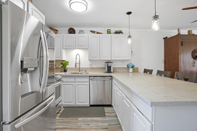 kitchen with kitchen peninsula, white cabinets, appliances with stainless steel finishes, a kitchen breakfast bar, and sink