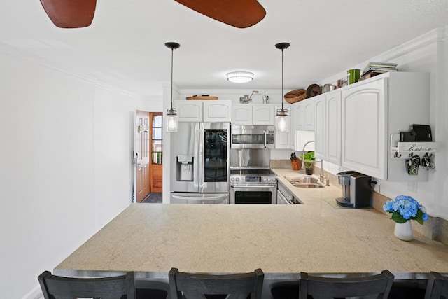 kitchen with decorative light fixtures, white cabinets, kitchen peninsula, and appliances with stainless steel finishes