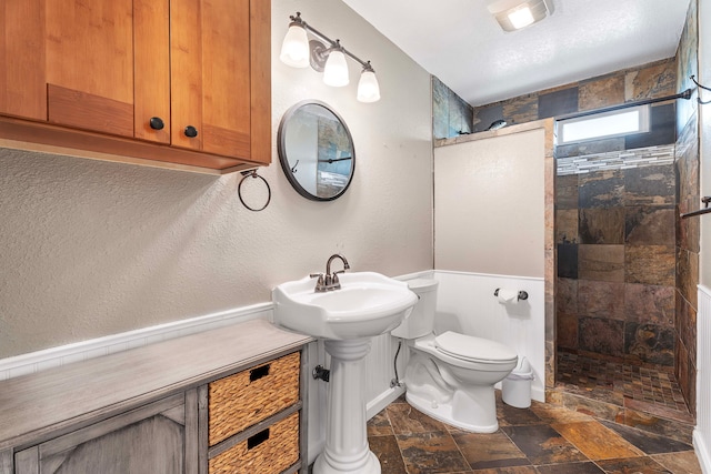 bathroom with sink, toilet, and tiled shower