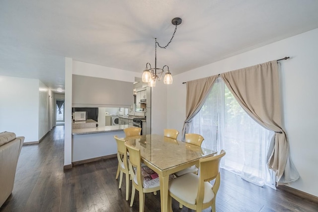 dining area featuring dark wood-style floors, washer / clothes dryer, baseboards, and an inviting chandelier