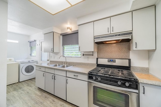 kitchen featuring washer and clothes dryer, light countertops, a sink, stainless steel gas range, and under cabinet range hood