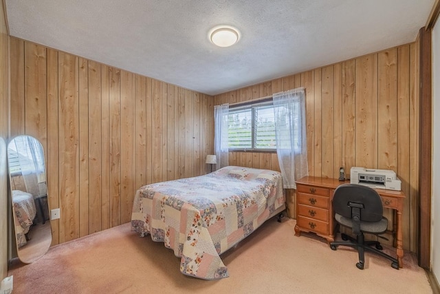 bedroom with light carpet, a textured ceiling, and wooden walls