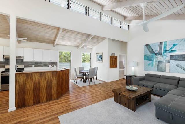 living room featuring light hardwood / wood-style flooring, wood ceiling, beamed ceiling, ceiling fan, and high vaulted ceiling