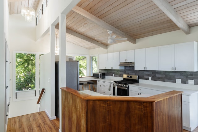 kitchen featuring stainless steel appliances, backsplash, white cabinets, and lofted ceiling with beams