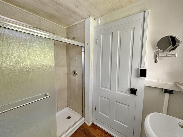 bathroom with toilet, a shower with door, and hardwood / wood-style floors