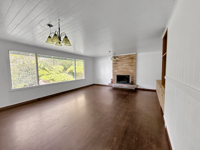 unfurnished living room featuring a fireplace, dark hardwood / wood-style flooring, brick wall, and a wealth of natural light