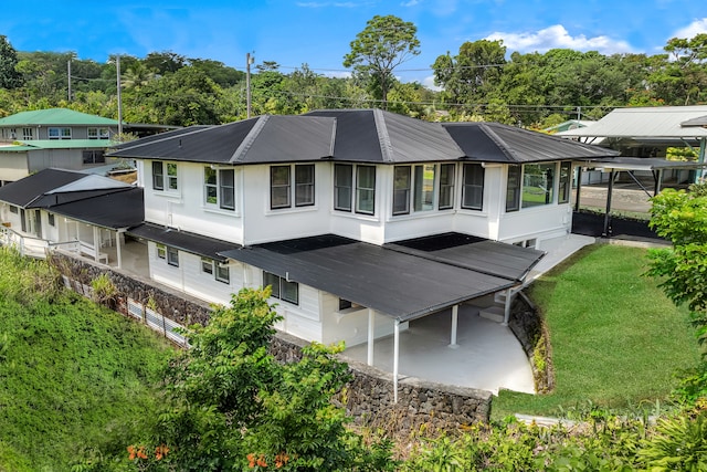 back of property with a yard, a carport, and a sunroom