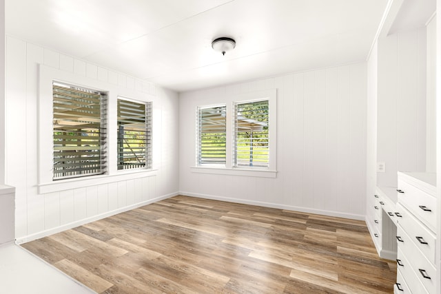 unfurnished room featuring light wood-type flooring and wood walls