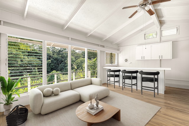 living room featuring wood walls, a textured ceiling, a wealth of natural light, and light wood-type flooring