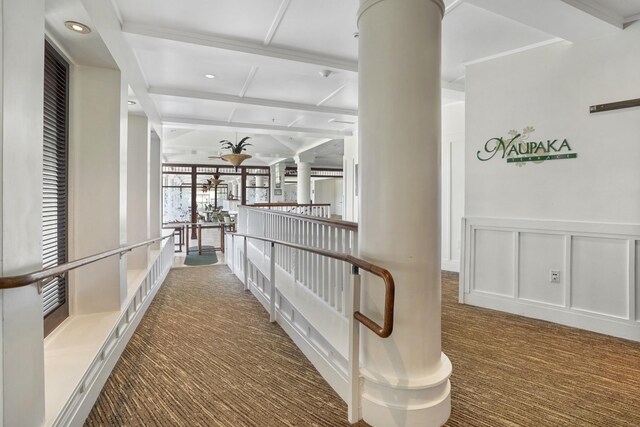 hallway featuring light carpet, ornate columns, and beam ceiling