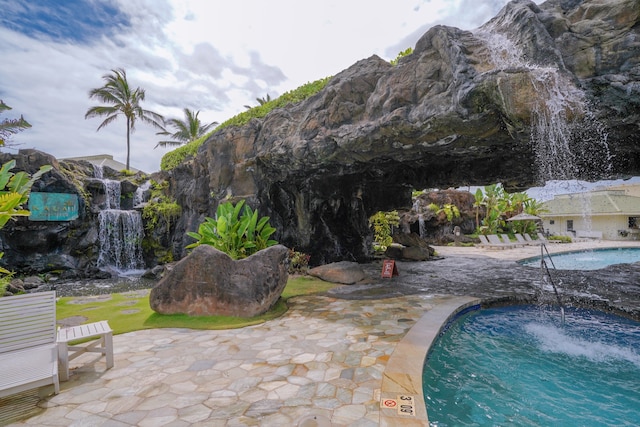 view of swimming pool with a mountain view, pool water feature, and a patio