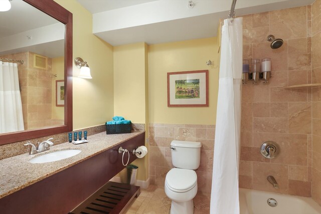 full bathroom featuring toilet, vanity, tile walls, tile patterned floors, and shower / bath combo