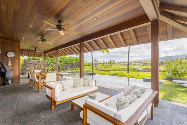 view of patio / terrace featuring outdoor dining area, ceiling fan, outdoor lounge area, and an in ground hot tub