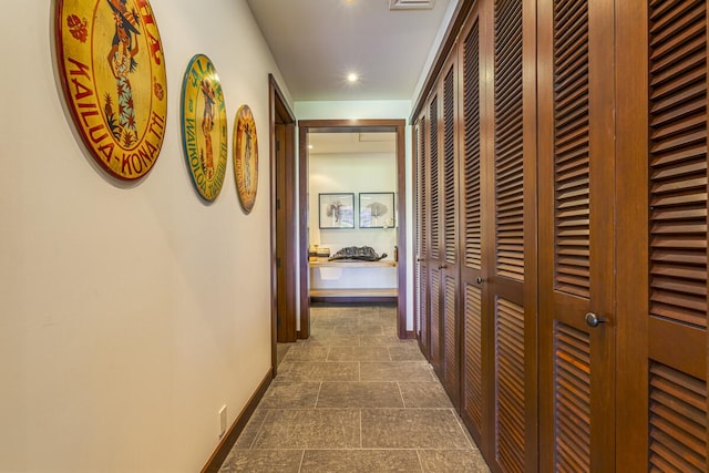 hallway with stone finish flooring, baseboards, and recessed lighting