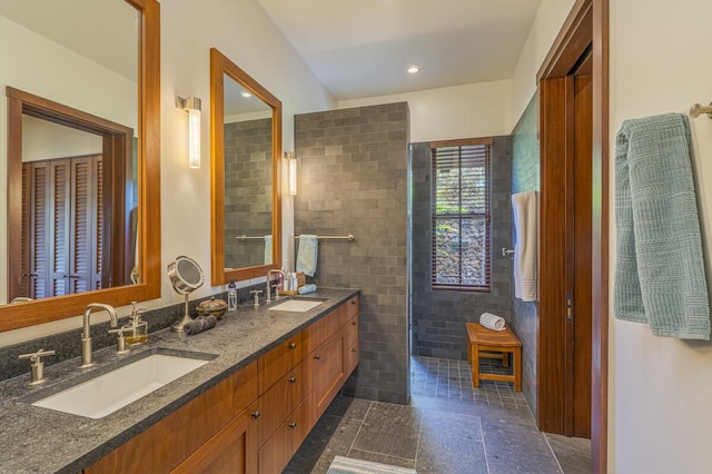 full bathroom with double vanity, tile walls, a walk in shower, and a sink