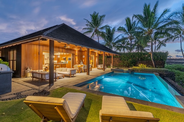 pool at dusk with outdoor lounge area, a yard, and a patio area