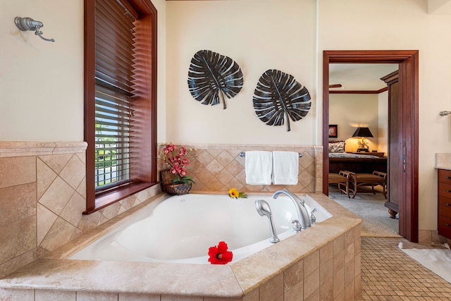 bathroom with ornamental molding, vanity, and tiled bath