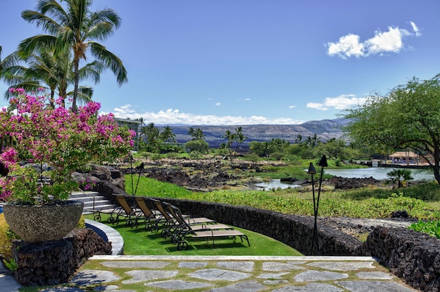 view of property's community featuring a water and mountain view and a lawn