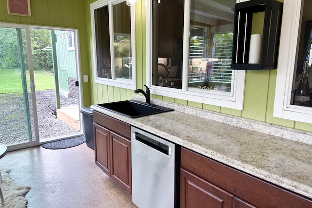 kitchen with dishwasher, light stone counters, and sink