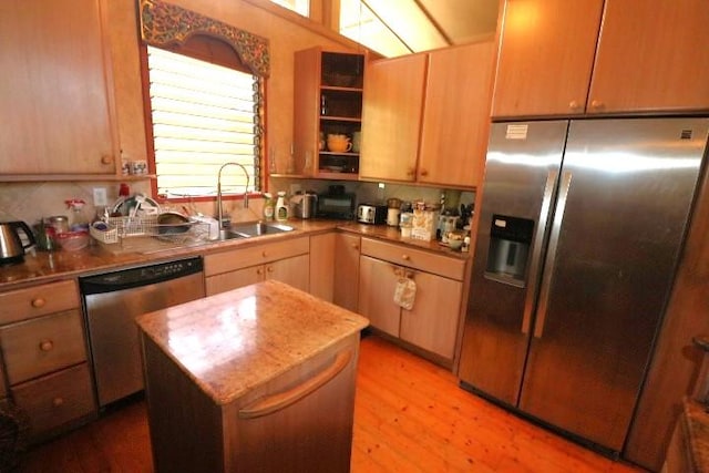 kitchen with stainless steel appliances, a kitchen island, sink, and light hardwood / wood-style flooring