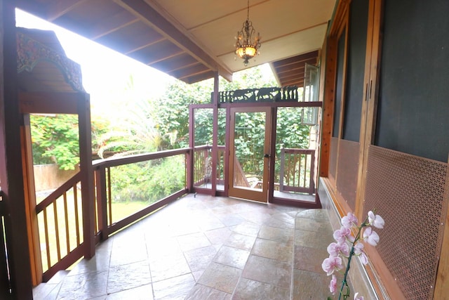 unfurnished sunroom featuring beam ceiling and a chandelier