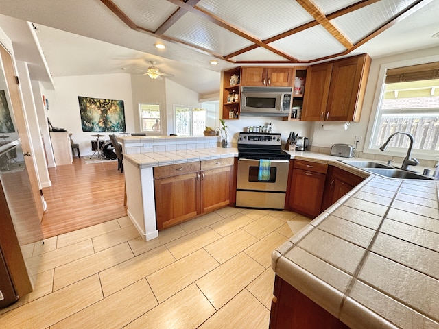 kitchen with sink, appliances with stainless steel finishes, tile counters, and a healthy amount of sunlight