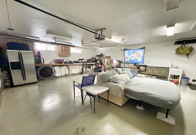 garage with a garage door opener, sink, and stainless steel refrigerator with ice dispenser