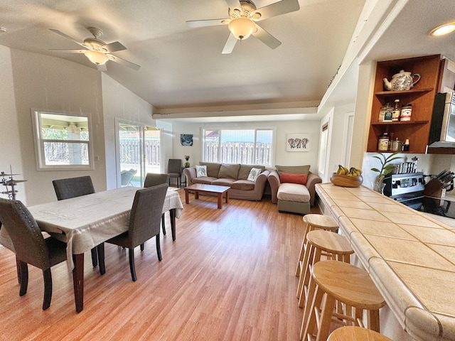 dining room featuring light hardwood / wood-style floors, ceiling fan, and vaulted ceiling