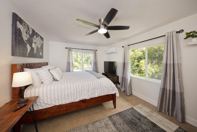 bedroom featuring multiple windows, a wall mounted AC, a textured ceiling, and ceiling fan