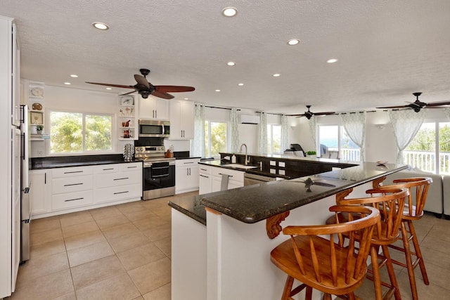 kitchen featuring sink, a breakfast bar area, appliances with stainless steel finishes, kitchen peninsula, and white cabinets