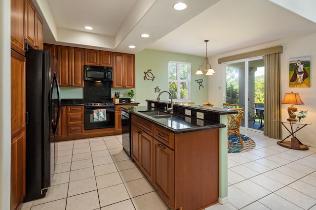 kitchen featuring light tile patterned floors, a kitchen island with sink, sink, and black appliances