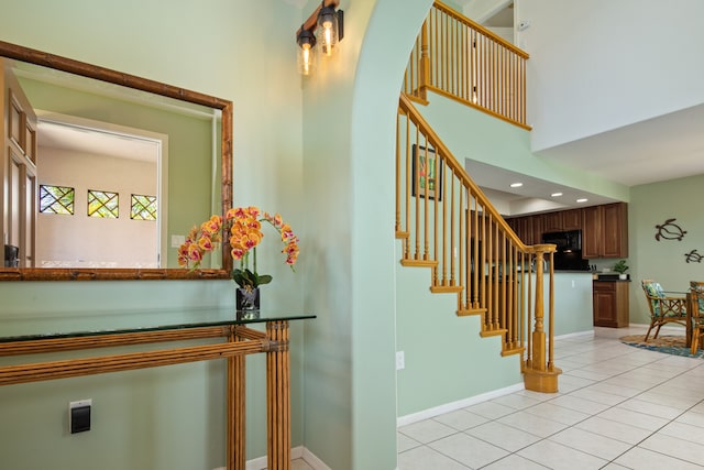 staircase featuring tile patterned floors and a high ceiling