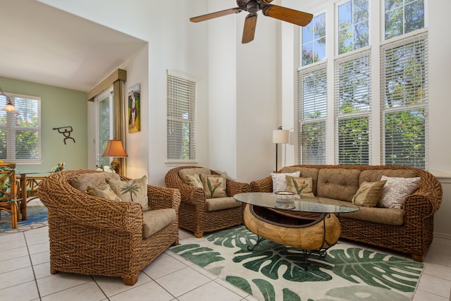 living area with ceiling fan, a high ceiling, and light tile patterned floors