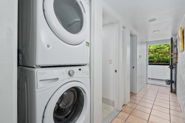 laundry room with light tile patterned flooring and stacked washer and clothes dryer