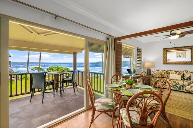 dining area featuring ornamental molding, a water view, wood-type flooring, and ceiling fan