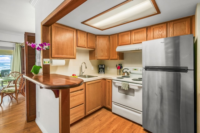 kitchen with stainless steel refrigerator, tasteful backsplash, light hardwood / wood-style flooring, white range with electric cooktop, and sink