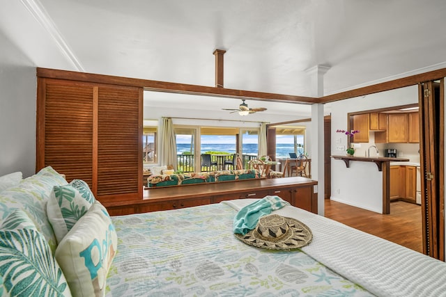 bedroom with a water view, hardwood / wood-style floors, crown molding, and sink