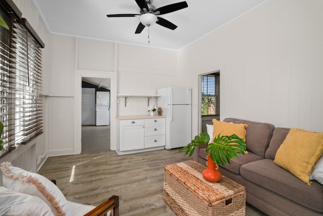 living room with light wood-type flooring, ceiling fan, and ornamental molding