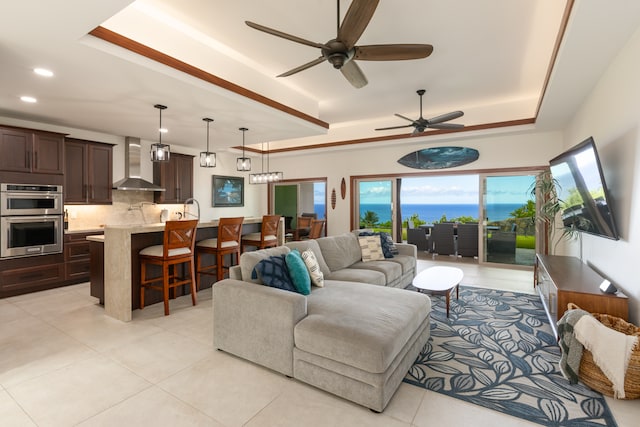 tiled living room featuring a tray ceiling, plenty of natural light, and ceiling fan