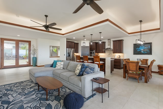 tiled living room with ceiling fan and a raised ceiling