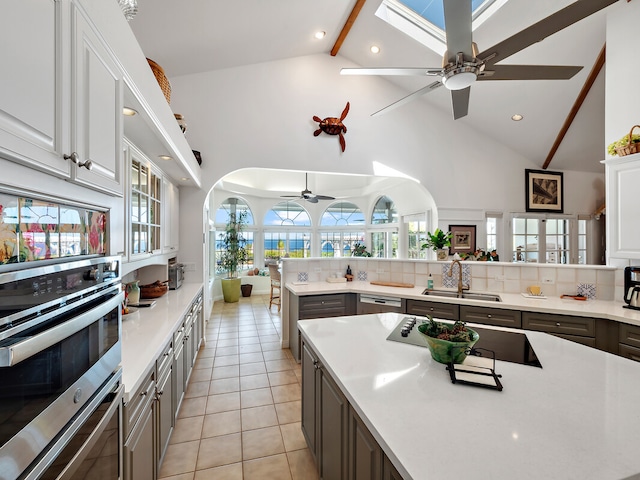 kitchen with light tile patterned floors, ceiling fan, beamed ceiling, sink, and high vaulted ceiling